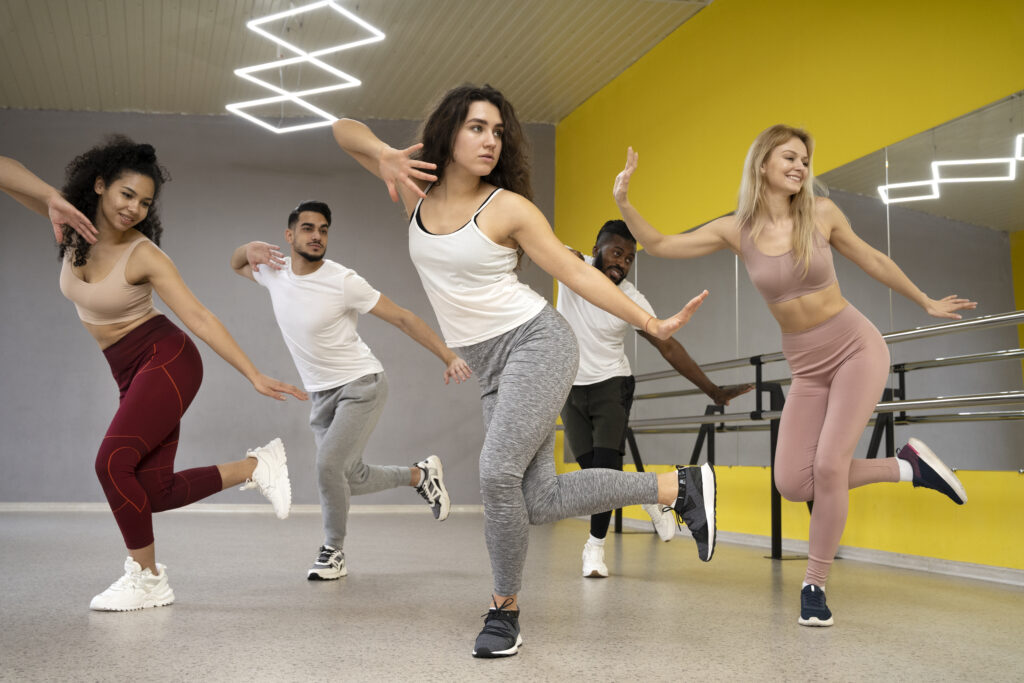 Group of energetic individuals performing an Aerobics Dance Workout in a modern fitness studio, combining dance, exercise, and fun for a healthy lifestyle