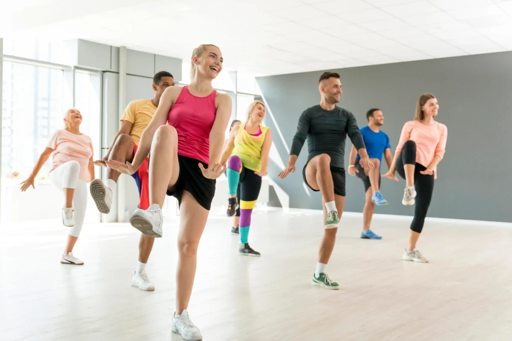 Group of people enjoying a high-energy Bollywood dance workout in a bright fitness studio.”